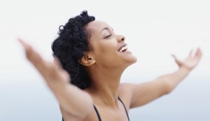 Happy and healthy African American woman relaxing with open arms outdoors